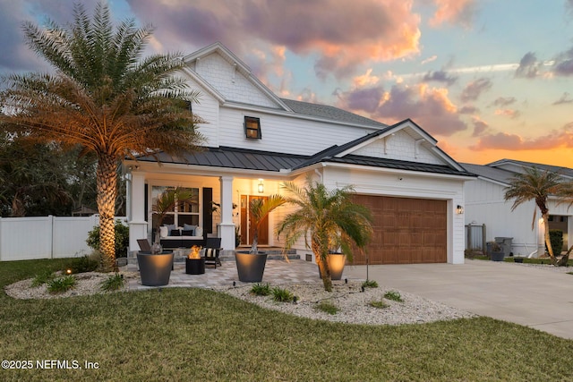 view of front of home featuring concrete driveway, a standing seam roof, fence, metal roof, and a garage