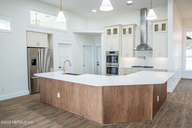 kitchen with wall chimney exhaust hood, stainless steel appliances, a large island, and hanging light fixtures