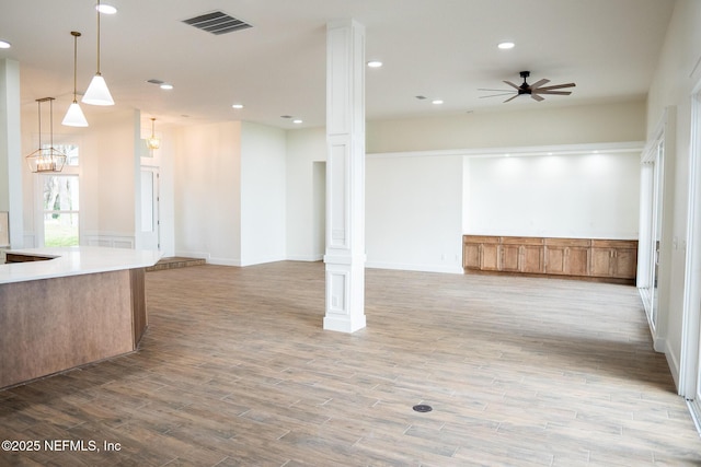 interior space featuring ornate columns, ceiling fan, and light wood-type flooring