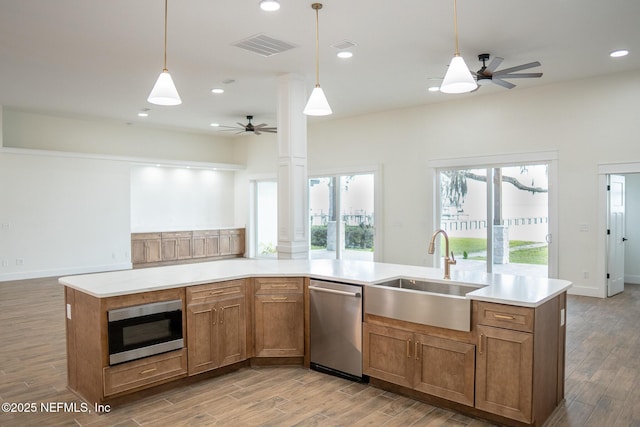 kitchen with decorative light fixtures, built in microwave, an island with sink, sink, and stainless steel dishwasher