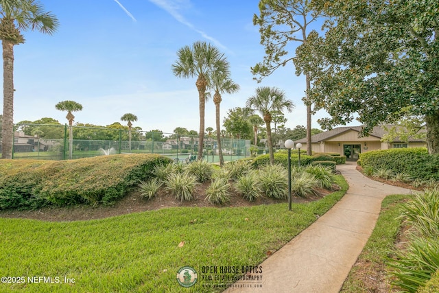 view of property's community featuring a lawn and fence