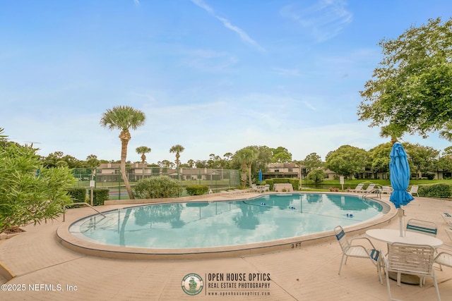 community pool featuring fence and a patio