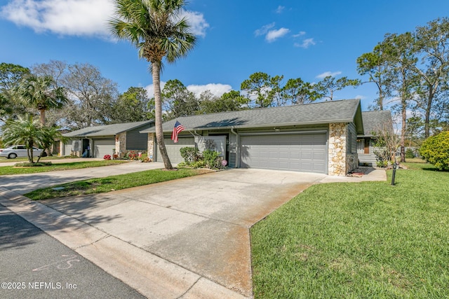 view of front of home featuring roof with shingles, an attached garage, a front yard, stone siding, and driveway