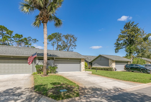 view of front of home with a garage, concrete driveway, a front lawn, and stone siding