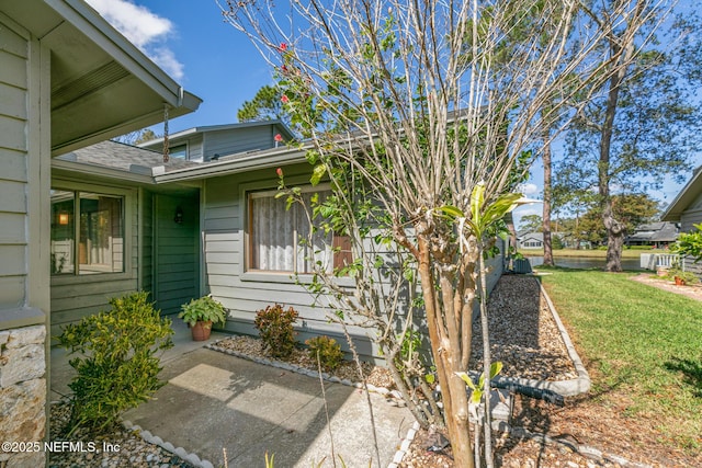 entrance to property with a shingled roof and a yard