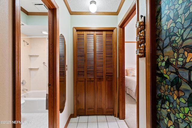 hall featuring light tile patterned floors, ornamental molding, and a textured ceiling