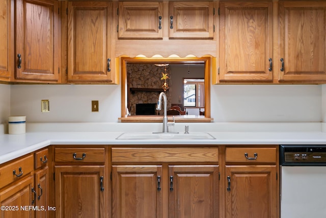 kitchen featuring brown cabinetry, light countertops, and a sink