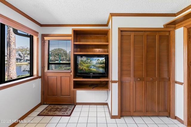 interior space featuring a textured ceiling, ornamental molding, and light tile patterned floors