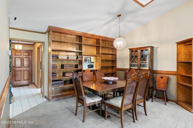 dining space featuring light tile patterned floors, a chandelier, light carpet, vaulted ceiling, and ornamental molding