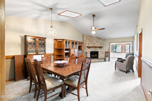 dining area with a fireplace, lofted ceiling, light colored carpet, a textured ceiling, and ceiling fan with notable chandelier