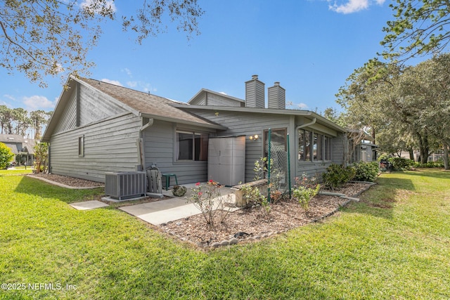 back of property featuring a chimney, cooling unit, and a yard