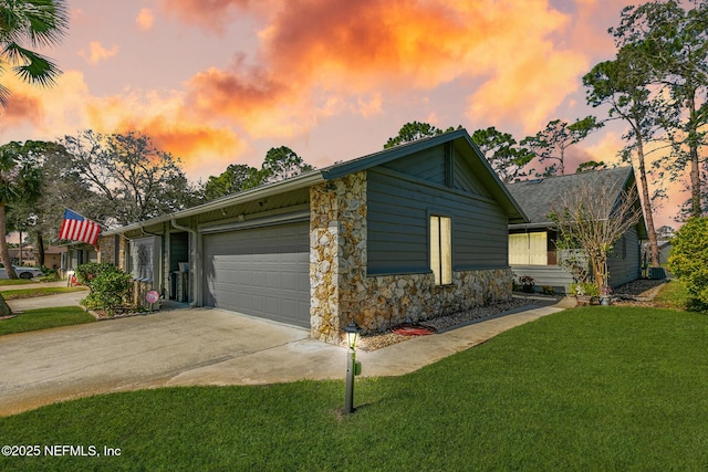 exterior space with a garage, stone siding, a lawn, and driveway