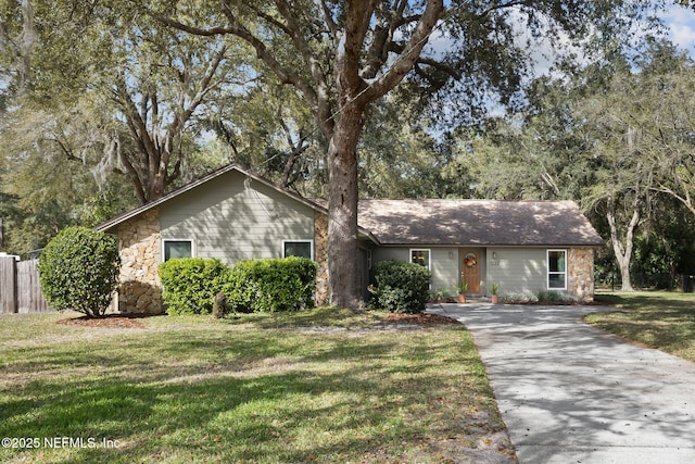 single story home featuring stone siding, a front yard, and fence