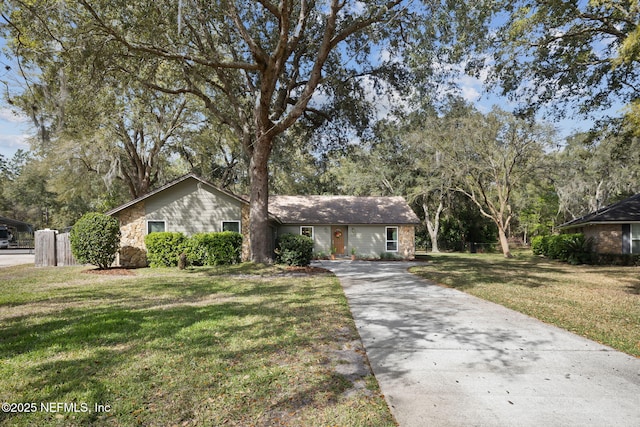 view of front facade featuring stone siding, concrete driveway, and a front yard