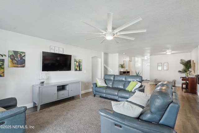 living room featuring ceiling fan, a textured ceiling, and dark hardwood / wood-style flooring