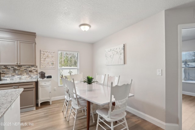 dining space with a textured ceiling and light hardwood / wood-style flooring