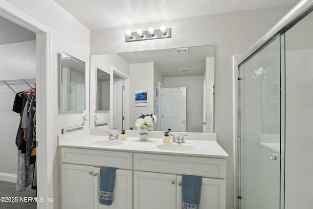 bathroom with an enclosed shower, vanity, and a textured ceiling