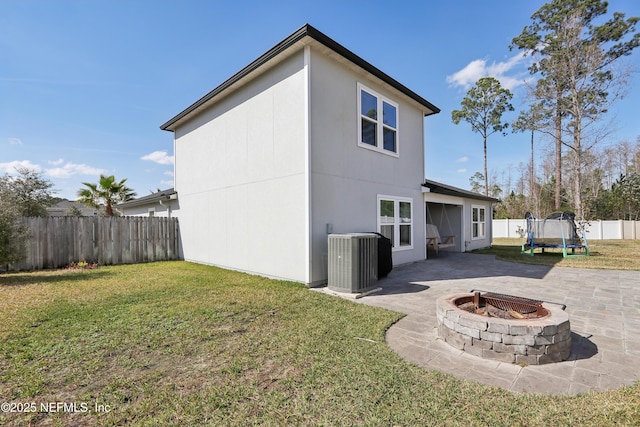 back of house with a patio, a fire pit, a trampoline, a yard, and central air condition unit