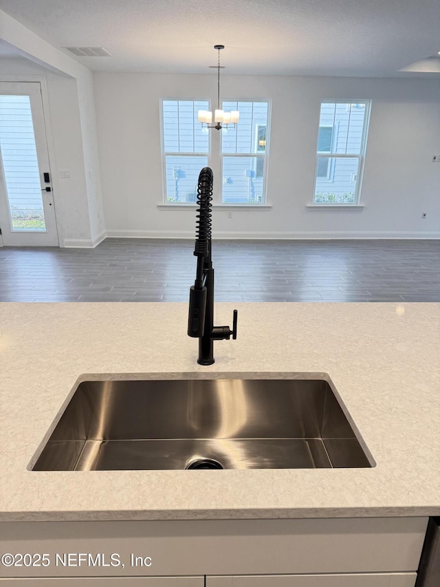 interior details with light countertops, decorative light fixtures, a sink, and visible vents