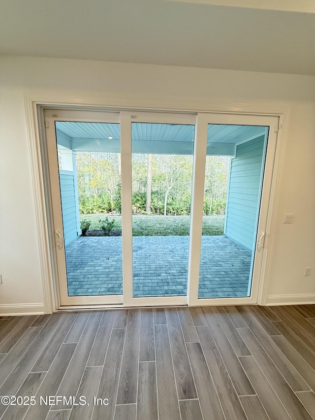 doorway with a wealth of natural light, baseboards, and wood tiled floor