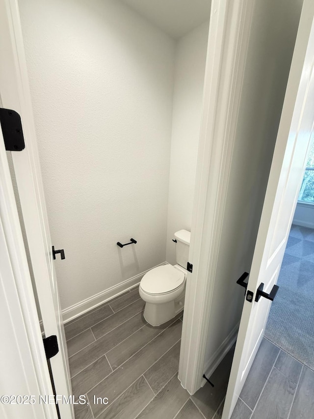 bathroom featuring baseboards, toilet, and wood tiled floor