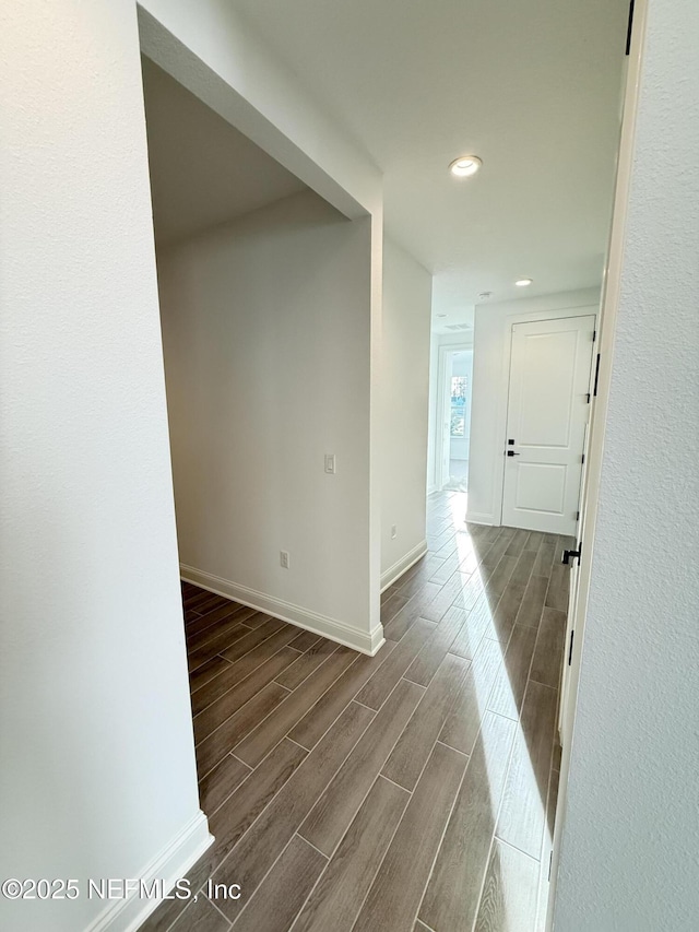 corridor with wood tiled floor, baseboards, and recessed lighting