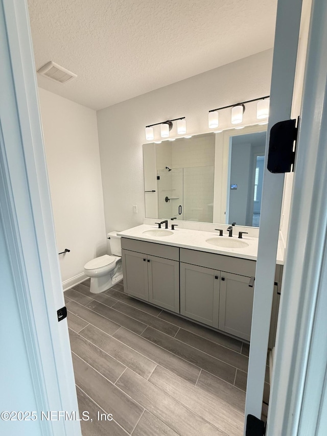 full bath with wood finish floors, visible vents, a sink, and double vanity