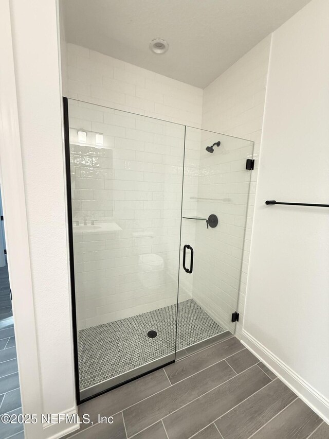 bathroom featuring baseboards, a stall shower, and wood tiled floor