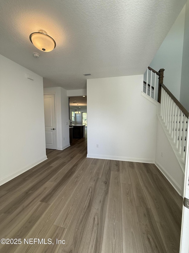 spare room with visible vents, baseboards, wood finished floors, stairs, and a textured ceiling