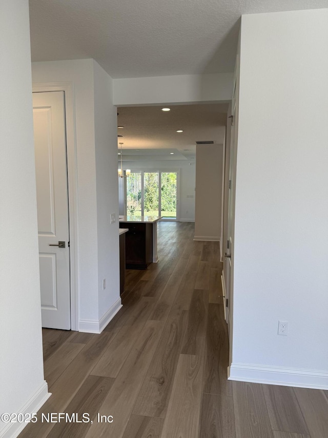 hall featuring dark wood-style floors, baseboards, a textured ceiling, and recessed lighting