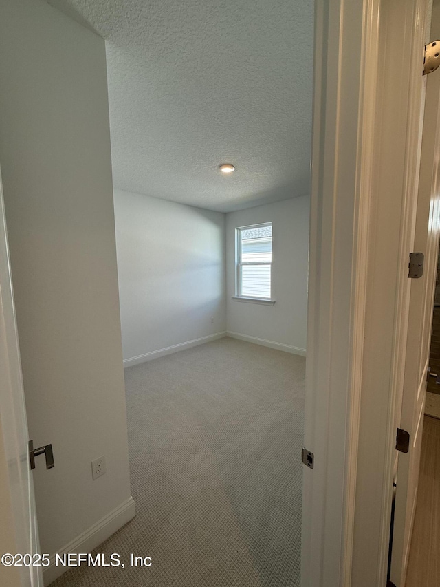 carpeted spare room with baseboards and a textured ceiling