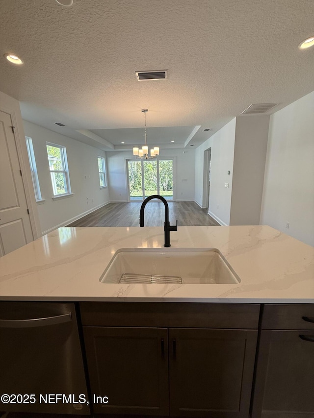 kitchen with visible vents, open floor plan, a sink, light stone countertops, and dishwasher