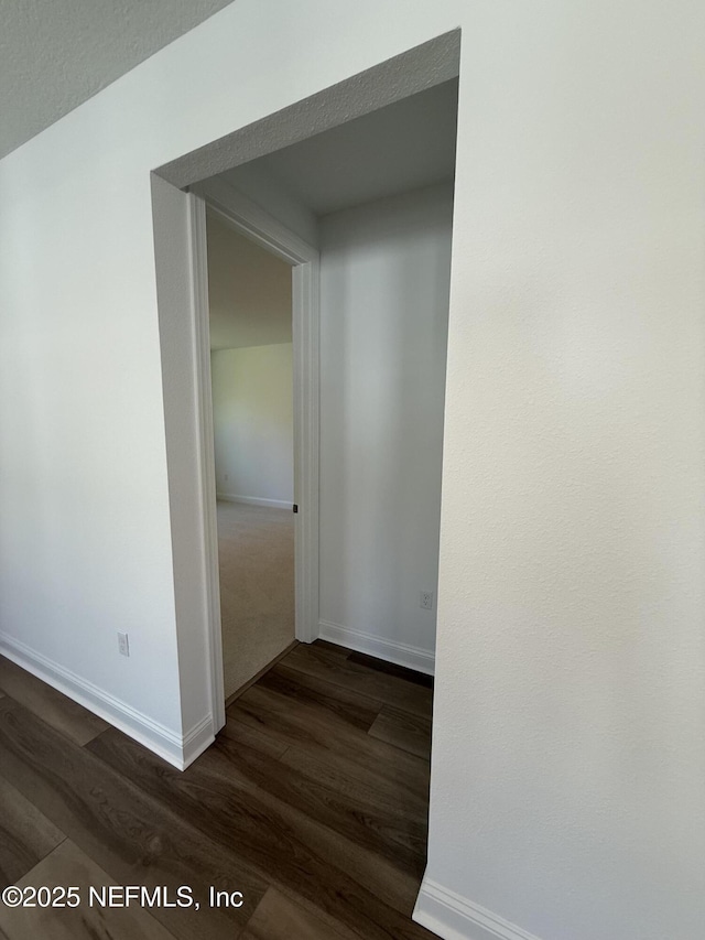 hall featuring dark wood-type flooring and baseboards