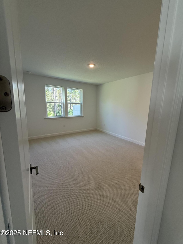 unfurnished room featuring baseboards and light colored carpet