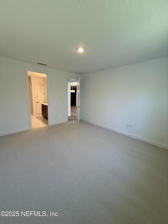 unfurnished bedroom featuring baseboards, visible vents, a textured ceiling, and light colored carpet