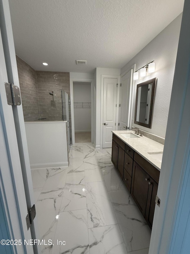 full bathroom with double vanity, visible vents, marble finish floor, a shower stall, and a sink