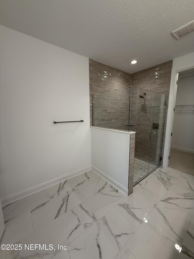 bathroom featuring a shower stall, visible vents, a walk in closet, and baseboards