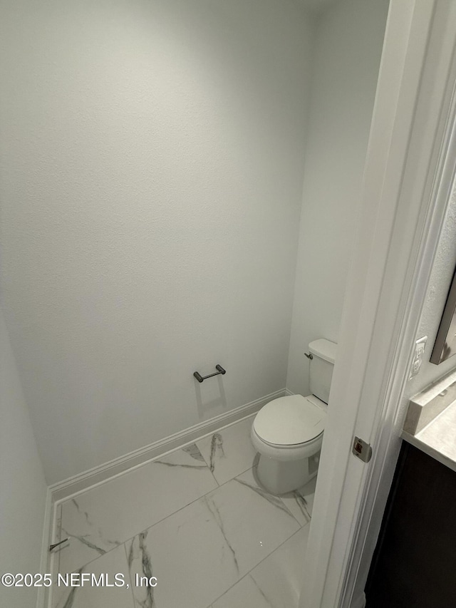 bathroom featuring marble finish floor, toilet, and baseboards