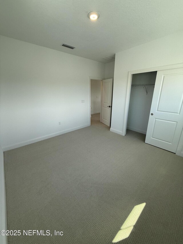 unfurnished bedroom featuring baseboards, carpet, visible vents, and a closet