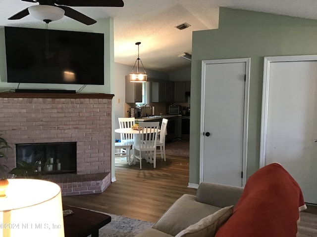 living room featuring sink, dark hardwood / wood-style flooring, vaulted ceiling, and a brick fireplace