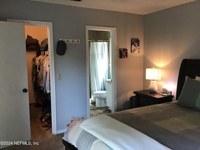 bedroom with connected bathroom, a textured ceiling, light carpet, a walk in closet, and a closet