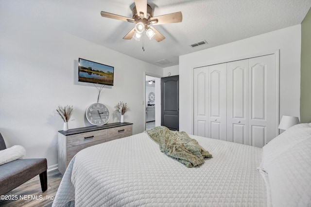 bedroom featuring hardwood / wood-style flooring, ensuite bath, ceiling fan, a textured ceiling, and a closet