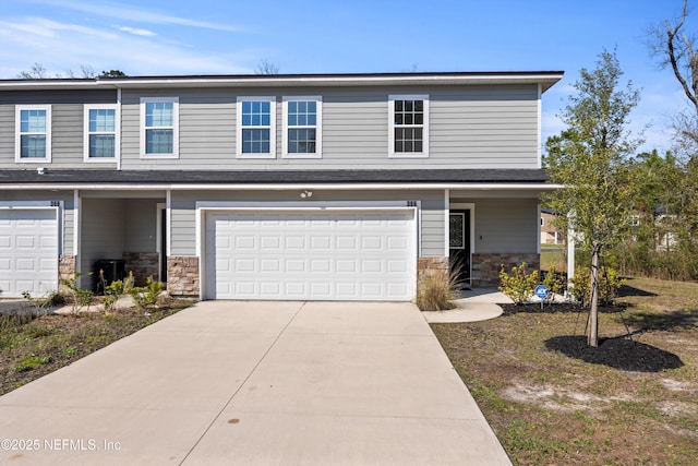 view of front of house with stone siding, an attached garage, and concrete driveway