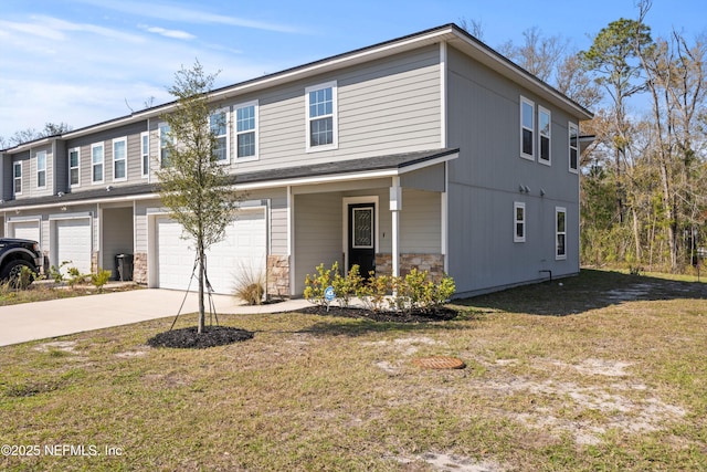 view of front of home featuring stone siding, concrete driveway, an attached garage, and a front yard