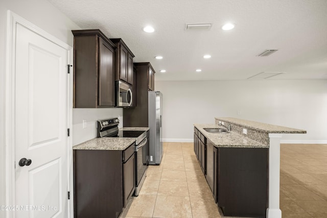 kitchen with light tile patterned floors, stainless steel appliances, a sink, visible vents, and dark brown cabinets