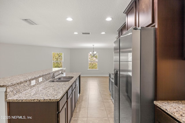 kitchen with light tile patterned flooring, dark brown cabinetry, a sink, visible vents, and appliances with stainless steel finishes