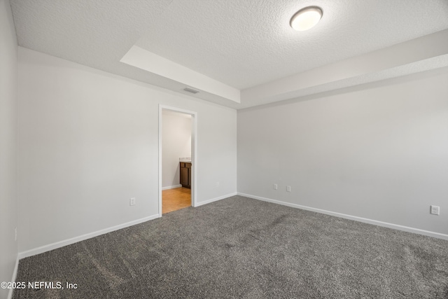 unfurnished bedroom with baseboards, visible vents, a tray ceiling, a textured ceiling, and carpet floors