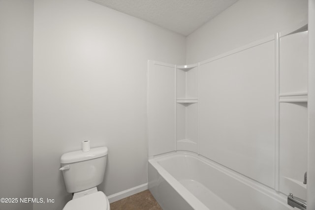 bathroom with toilet, baseboards,  shower combination, and a textured ceiling