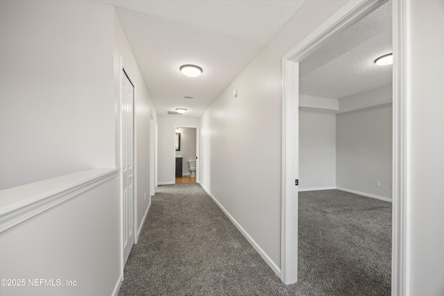 hall with carpet, a textured ceiling, and baseboards