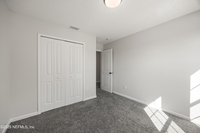 unfurnished bedroom with baseboards, visible vents, carpet, a textured ceiling, and a closet